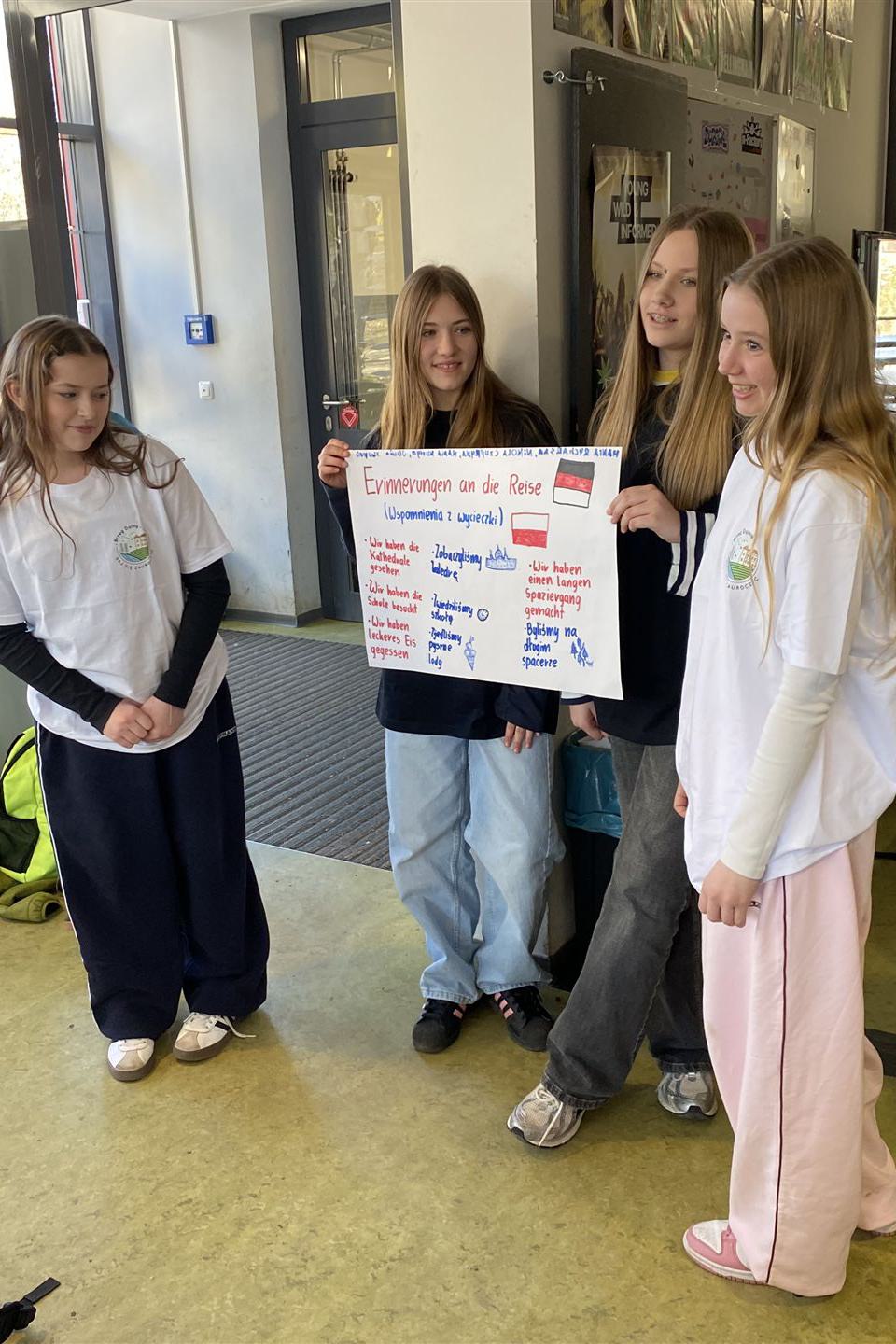 Schülerinnen zeigen ein Plakat aus einer Gruppenarbeit
