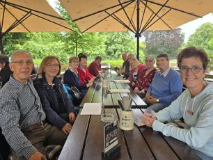 Eine Gruppe von Personen sitzt in einem Biergarten an einem Tisch