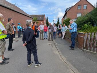 Eine Gruppe steht auf der Straße und hört einem Referenten zu